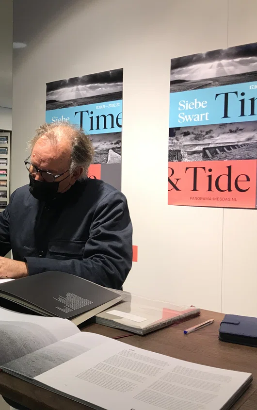 Fotograaf Siebe Swart signeert boeken in de museumwinkel van Museum Panorama Mesdag