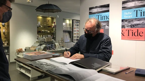 Fotograaf Siebe Swart signeert boeken in de museumwinkel van Museum Panorama Mesdag